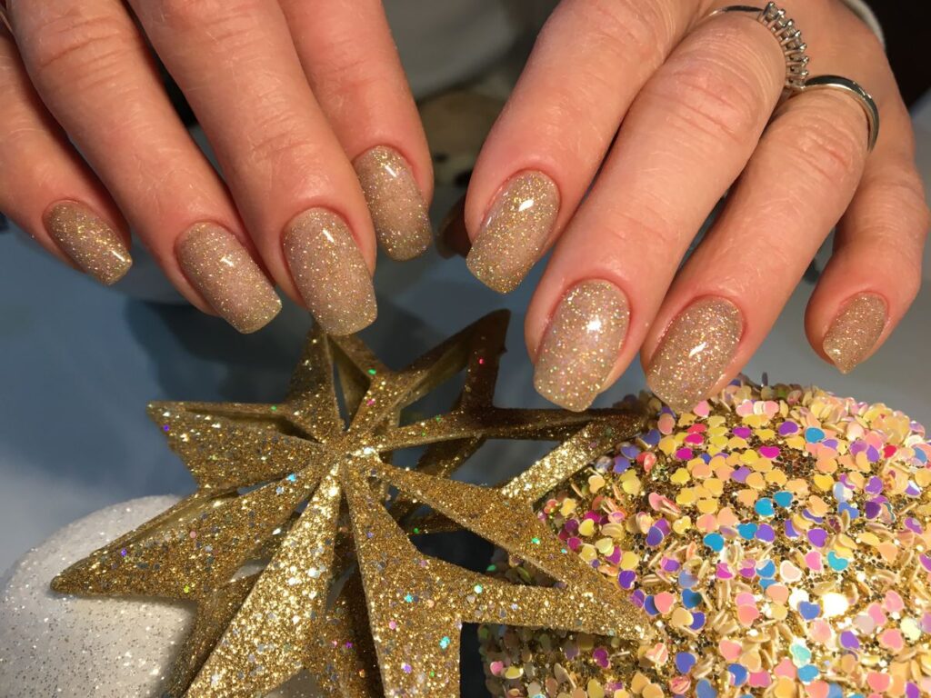 Gold glittered nails with small star decorations for a party manicure