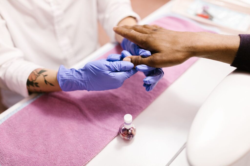 Manicurist wearing protective gloves during a treatment, showing the studio hygiene standards