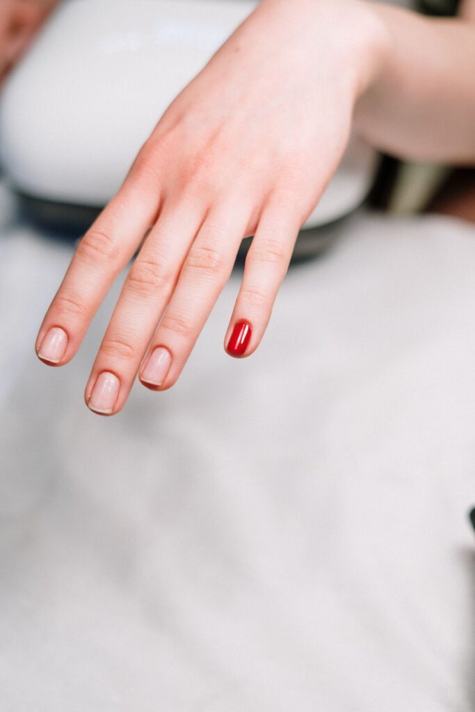Minimal manicure with a single red painted accent nail