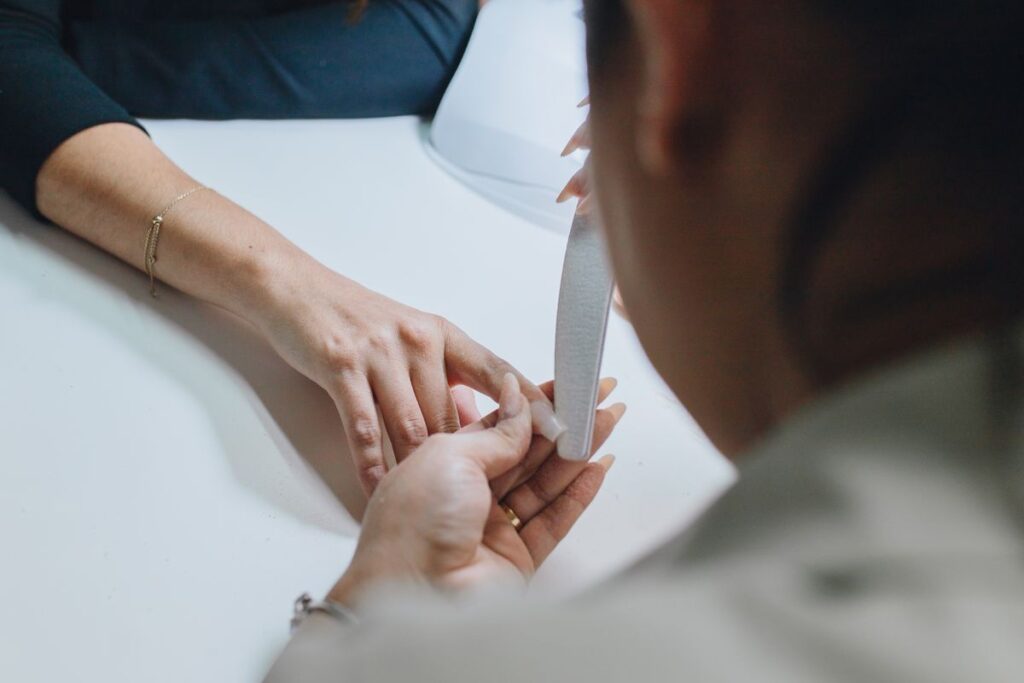 Manicurist shaping and filing a client nail during a professional manicure