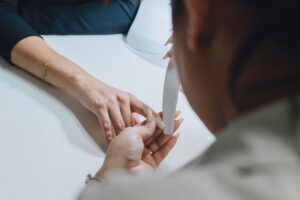 Manicurist shaping and filing a client nail during a professional manicure