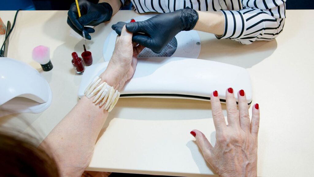 Overhead view of red nail polish being applied during a salon manicure