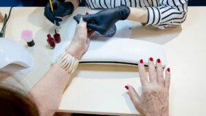 Overhead view of red nail polish being applied during a salon manicure